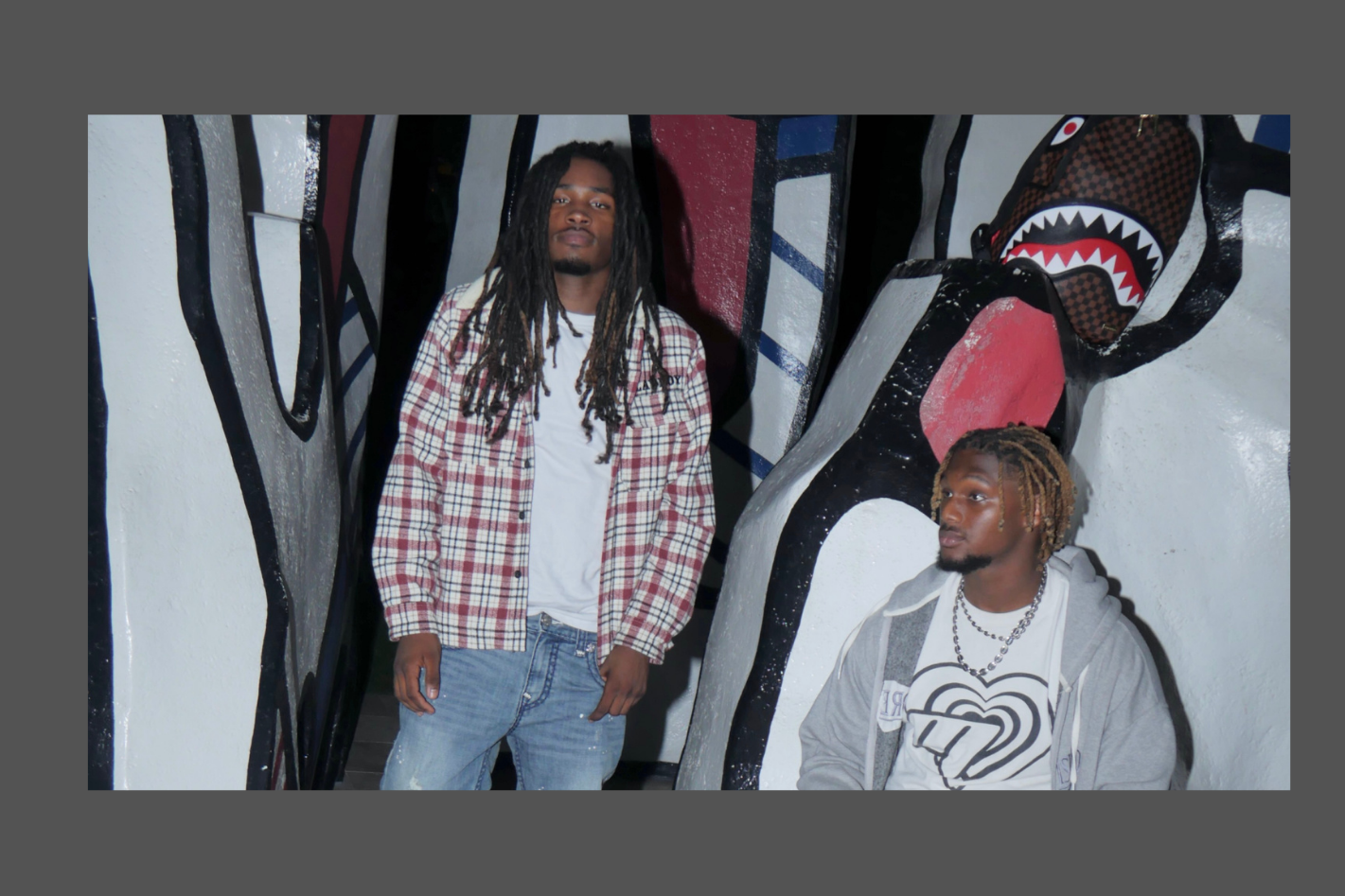 Two people standing in front of a colorful mural with text about Mafia of Baptiste Magazine.